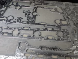 Close-up of wet machined metal part with circular and slot cut-outs