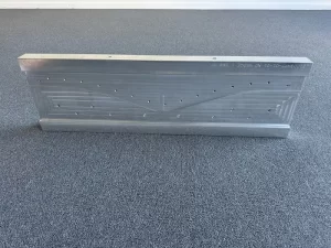 Front facing view of aluminium machined block with symmetrical hole pattern