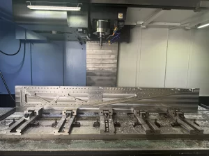 Front view of large machined metal block on CNC bed