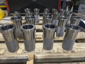 Precision machined cylindrical metal parts arranged on a wooden pallet