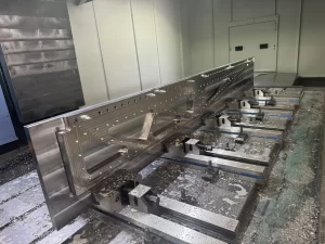 Shiny aluminium component held by modular vices on CNC