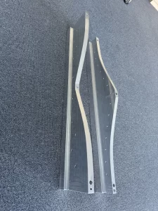 Top-down view of two CNC-cut aluminium brackets with curved profiles