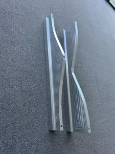 Two precision machined aluminium brackets placed vertically on carpet