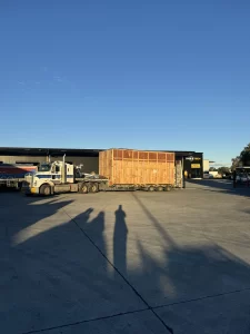 Wide shot of truck and oversized wooden crate at industrial facility