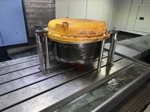 Yellow industrial component clamped onto a metal machine surface